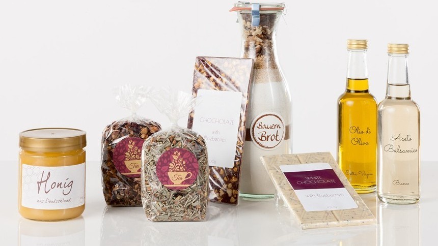 Un borcan de miere, două pachete de ierburi, săpun în sticlă decorativă și două sticle de ulei cu etichete transparente