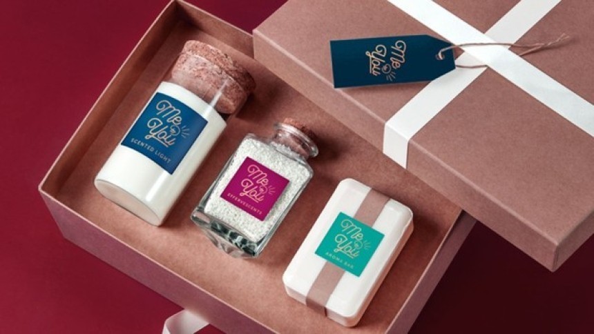Un set cadou deschis într-o cutie, care conține trei produse cosmetice cu etichete "Me & You": o lumânare parfumată, săruri de baie într-un borcan și un săpun solid.