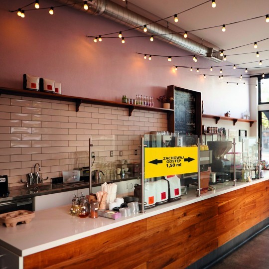 Barul unei cafenele cu etichete pentru păstrarea distantei plasate pe vitrina despărţitoare