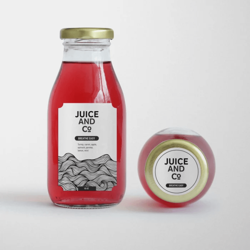 Compoziție din două sticle de suc. Sticla așezată pe o parte, care conține un lichid roșu, are o etichetă albă, dreptunghiulară, pe care scrie 