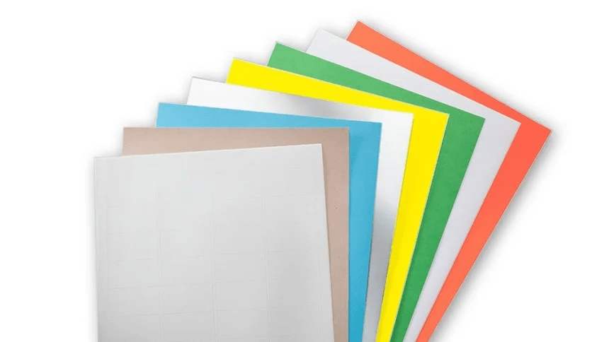 Un evantai de coli de etichete multicolore, prezentând materialele disponibile în culori precum alb, kraft, albastru, galben, verde și portocaliu.