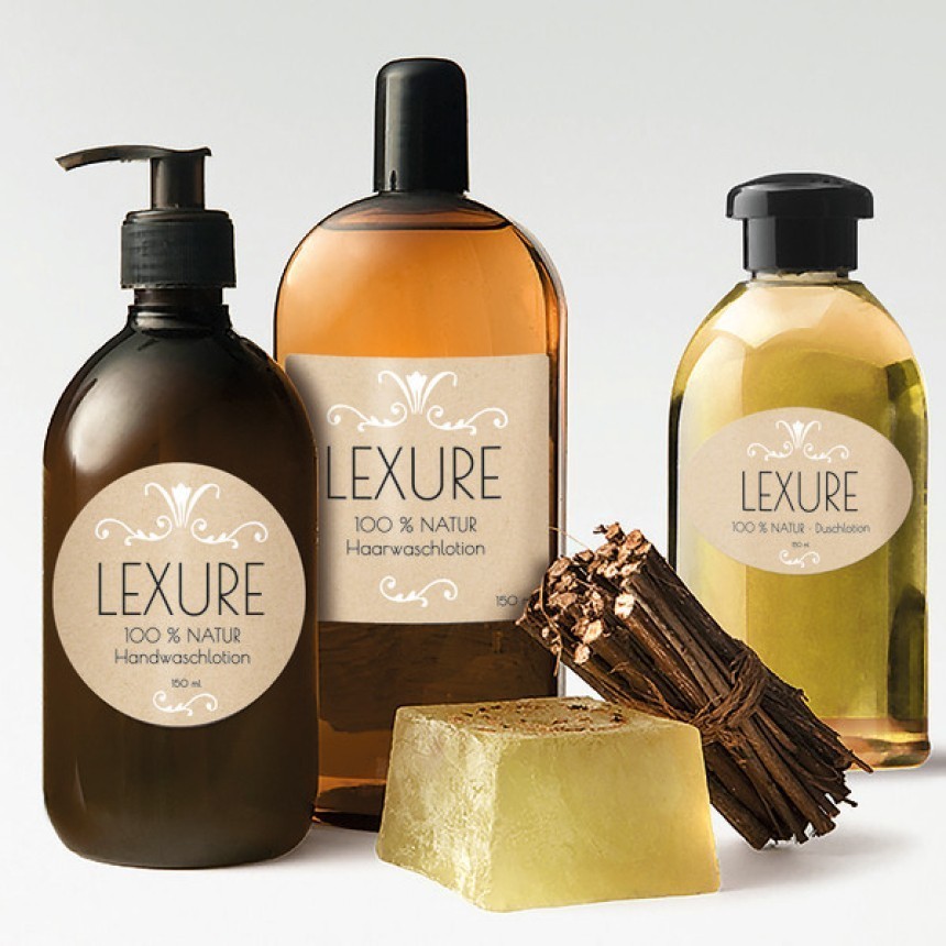 O selecție de produse cosmetice naturale marca "Lexure". În imagine se văd o sticlă maro cu dozator pentru săpun de mâini, o sticlă de culoarea chihlimbarului cu șampon de păr și o sticlă galben deschis cu gel de duș. Alături se află un săpun solid și un mănunchi de crenguțe uscate.