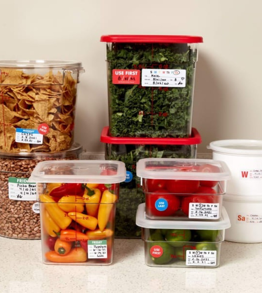Recipiente de depozitare a alimentelor de diferite dimensiuni, umplute cu legume. Fiecare recipient are o etichetă cu data de expirare, ca parte a sistemului FIFO.