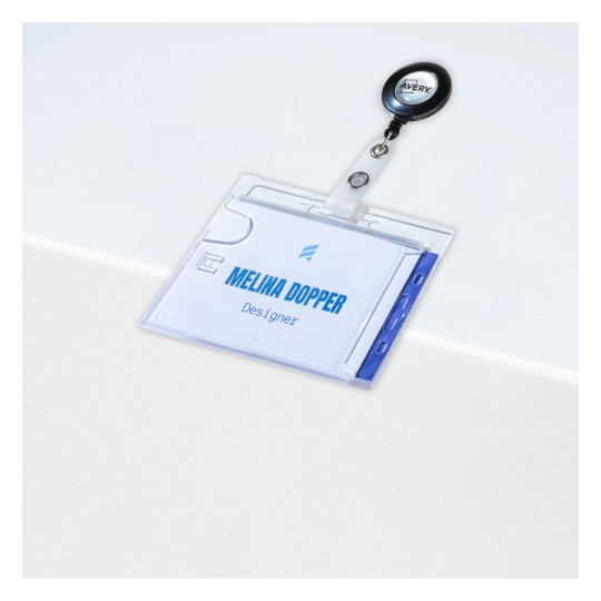 Imaginea prezintă un suport de card ID din plastic transparent, atașat la un dispozitiv retractabil pentru badge. Cardul ID conține numele 'Melina Dopper' și indică ocupația 'Designer'. Fundalul este o suprafață de culoare deschisă.