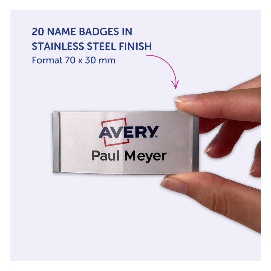 Imaginea afișează o mână ținând un ecuson de nume din oțel inoxidabil cu textul 'Avery Paul Meyer' pe el. Se menționează 20 de ecusoane disponibile cu finisaj din oțel inoxidabil, având dimensiunea de 70 x 30 mm.