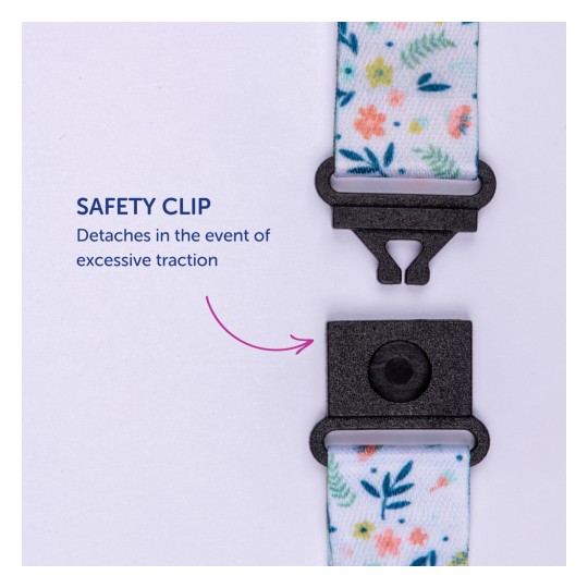 Imaginea arată o clemă de siguranță cu material decorativ atașat, etichetată cu instrucțiuni care indică faptul că se detașează sub tracțiune excesivă.