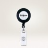 Imaginea arată un suport retractabil pentru ecuson, cu un vârf circular negru pe care este afișat logo-ul Avery și o curea albă cu un buton de prindere pentru atașarea cardurilor de identificare sau ecusoanelor.